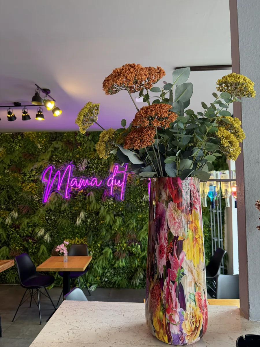 Blumen auf dem Tisch, im Hintergrund der Neon-Schriftzug